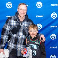Gentleman and young boy posing for photo in front of GV Alumni backdrop